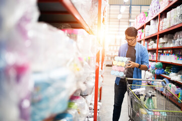 Asian man shopping. Handsome smiling young man shopping for household items with supermarket and shopping cart.