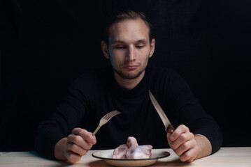 a young man is sitting at an empty table with a plate of raw chicken on it, the concept of a bad Thanksgiving