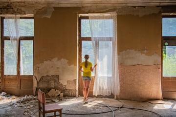 the room of an old abandoned building, the girl in the zhet looks out the window.