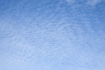 Sunny blue sky with a cover of light textured clouds, as a nature background
