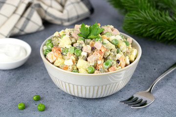Russian Olivier salad of vegetables, sausage and mayonnaise on a gray background. Selective focus.