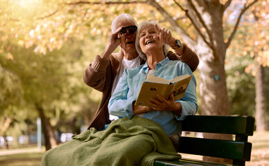 Park, bench and binoculars with a senior couple birdwatching together outdoor in nature during summer. Spring, love and book with a mature man and woman bonding while sitting in a garden for the view
