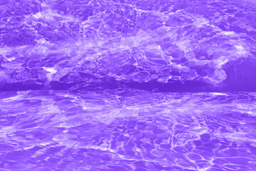 Defocus blurred transparent purple colored clear calm water surface texture with splashes and bubbles. Trendy abstract nature background. Water waves in sunlight with copy space. Pink watercolor shine