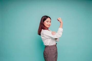 Excited Asian woman wearing a white shirt showing strong gesture by lifting her arms and muscles smiling proudly