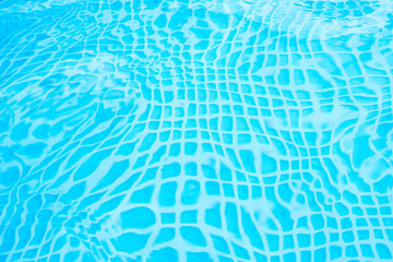 pattern of water of swimming pool with light in it and pool's stairway, a lot of space for text over blue water with play of light and shadow on pools bottom. Detail of beautiful swimming pool.