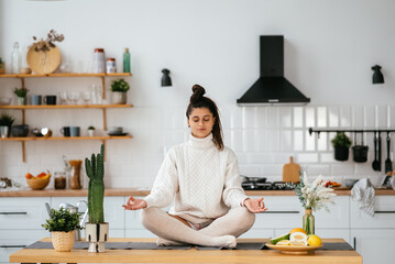 Young woman in lotus position sitting on the table