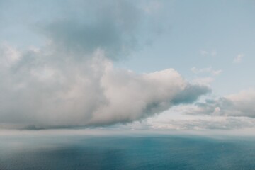 Naklejka na ściany i meble Aerial view. The drone flies over foggy and fluffy clouds. Blue sky sun and sea fog. Abstract aerial nature summer ocean sunset sea and sky background. Horizon. Vacation, travel and holiday concept