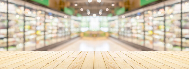 Empty wood table top with supermarket grocery store aisle and shelves blurred background