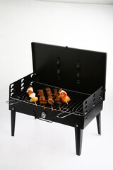 Mini grill with skewers on it, against a white background