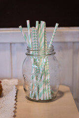 Green striped straws on a transparent glass pot on a party