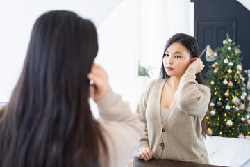 Young beautiful asian woman looking at her reflection in the mirror and smiling