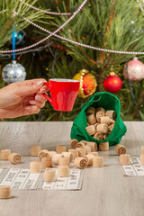 Woman's hand with cup of coffee and wooden barrel for a game in lotto
