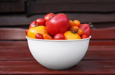 Bowl with fresh tomatoes on wooden surface, closeup