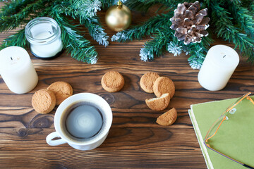 Obraz na płótnie Canvas A coffee mug, cookies, and a book with glasses against the backdrop of Christmas tree branches. The concept is New Year's vacations, time to read books.