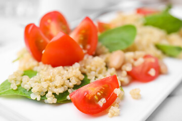Delicious quinoa salad with tomatoes, beans and spinach leaves, closeup