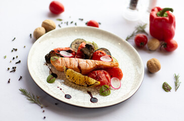Dish red fish with vegetables on a white background.