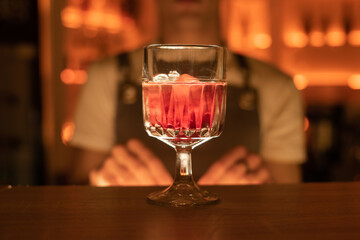 Red Fresh exotic alcoholic cocktail with ice in the bar. Red colorful Mojito. Bartender on background