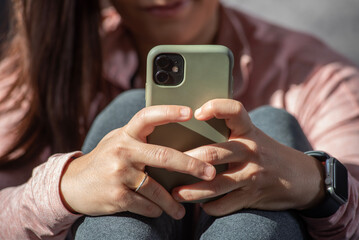 close-up detail of hands with mobile phone, behind fitness girl out of focus
