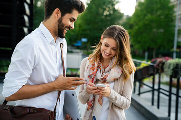 Happy businessman and woman with digital devices outdoors. Business people happiness concept