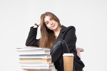 A student sits at a table with books and a glass of coffee. Beautiful long-haired girl in a jacket at a table on a white background