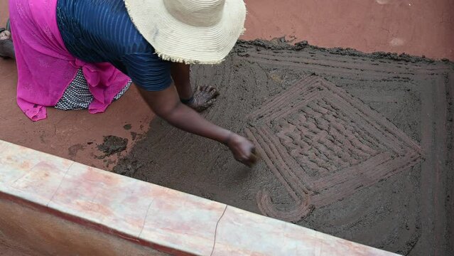 creation of a traditional pattern on the home patio made with cow dung in a tribal community in Makushu Village in Zimbabwe, Africa