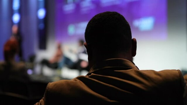 Back of people from audience perspective at conference listening to speaker