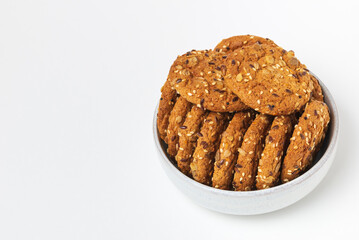 Oatmeal whole grain cookies with cereals in bowl isolated on white background.  Biscuits with sesame, sunflower and flax seeds with copy space
