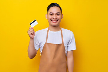 successful smiling young Asian man 20s barista employee wearing brown apron working in coffee shop,...