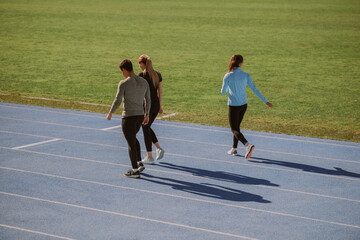 Fototapeta premium Three friends walking on a blue sports track