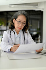 Portrait, Smart Asian aged female doctor focusing on reading a medical research case