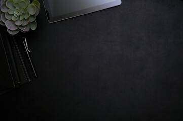 Modern stylish black workspace top view with tablet, pen, decor plant and copy space