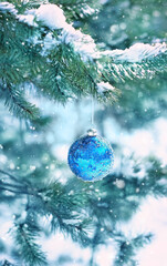 beautiful blue glass ball on snowy fir branch, abstract natural background. festive winter season....