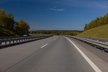Fototapeta premium Highway wide road, transport and blue sky with clouds on a summer day