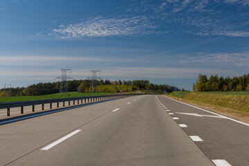 Fototapeta premium Highway wide road, transport and blue sky with clouds on a summer day