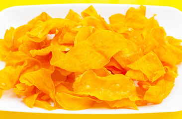 Sweet potato chips on yellow background.
