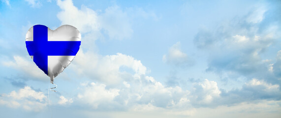 Flag of Finland on heart-shaped balloon against sky clouds background. Education, charity, emigration, travel and learning. Finnish language concept
