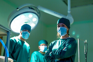 Portrait  surgeon and nurse with medical mask standing with arms crossed in operation theater at a...
