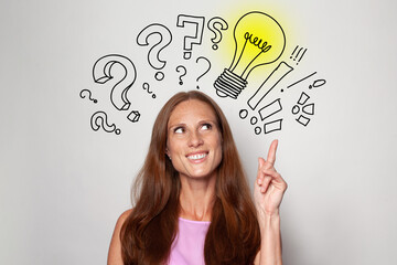 Smiling happy beautiful brunette woman with yellow light bulbs and question marks above her head....