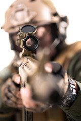 Fully equipped soldier with tactical gear aiming at enemy with sniper rifle. Shallow focus on scope iIolated on white background.