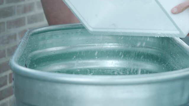 Pouring Box Of Ice Cubes Into Ice Bath Tub. closeup