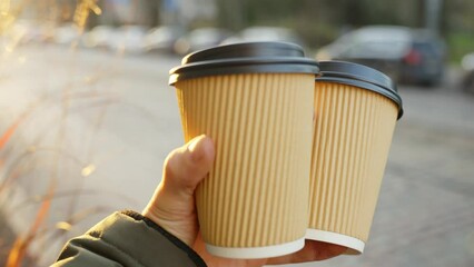 Person bring take away coffee cup for friend or lover on sunny day, POV