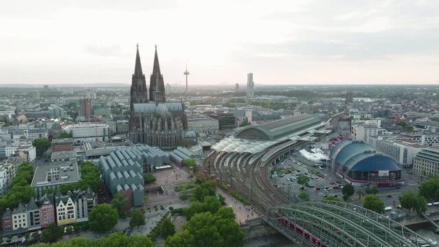 Drone films in Slowmotion the Cologne Cathedral, the Cologne Central Station, the Cologne Theather in the sunset, the drone moves down and the Rhine with the Hohenzoller Bridge comes into the picture