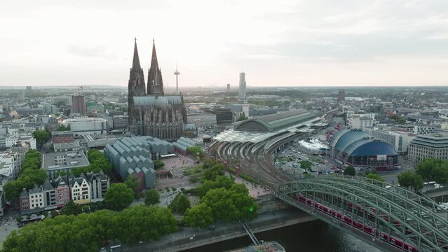 Drone films the Cologne Cathedral, the Cologne Central Station, the Cologne Theather in the sunset, the drone moves down and the Rhine with the Hohenzoller Bridge comes into the picture
