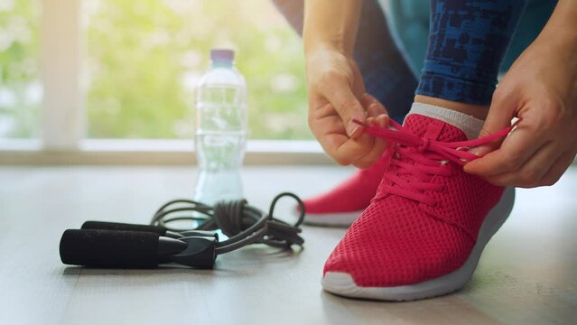 Woman tying shoelaces on sneakers going for training or jogging