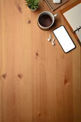 Simple workplace with smart phone, notebook and cup of coffee on wooden table. Top view, blank screen for your text