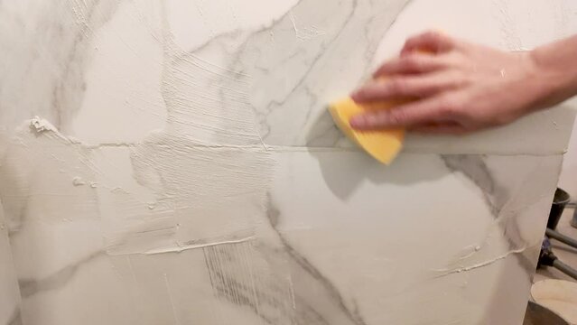 Clean fresh grout from ceramic tiles with sponge.