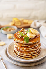 Celebrating Pancake day, american homemade breakfast. Banana gluten free pancakes with nuts and caramel on stone tabletop. Copy space.