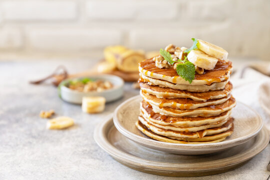 Celebrating Pancake day, american homemade breakfast. Banana gluten free pancakes with nuts and caramel on stone tabletop.