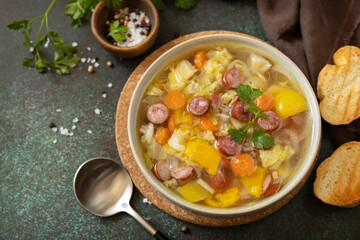 Traditional Zelnacka cabbage soup with sausages and vegetables in a bowl on a stone tabletop. Czech cuisine. Copy space.