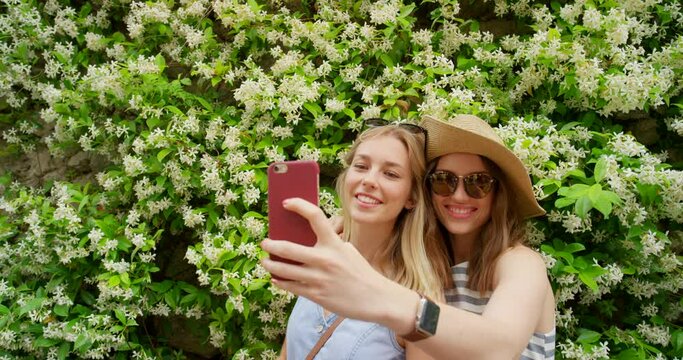 Phone, flowers and friends take a selfie for social media content in nature, park or backyard garden in summer. Smile, memory or happy girls taking pictures on holiday vacation with freedom in Italy